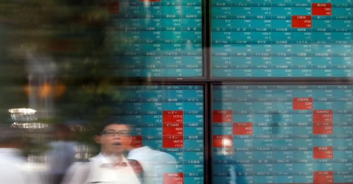 A man is reflected on a stock quotation board outside a brokerage in Tokyo