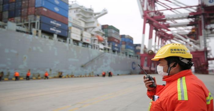 Foreman wearing a face mask works as a cargo ship docks at a container terminal of Qingdao port