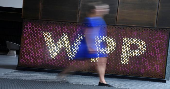 A woman walks past signage for WPP Group, the largest global advertising and public relations