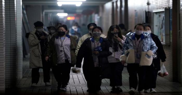 FILE PHOTO: Workers wearing masks walk outside their dormitory, in an electronics manufacturing
