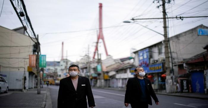 Men wearing protective face masks walk on a street at a residential community following an