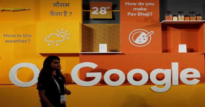 A woman walks past the logo of Google during an event in New Delhi