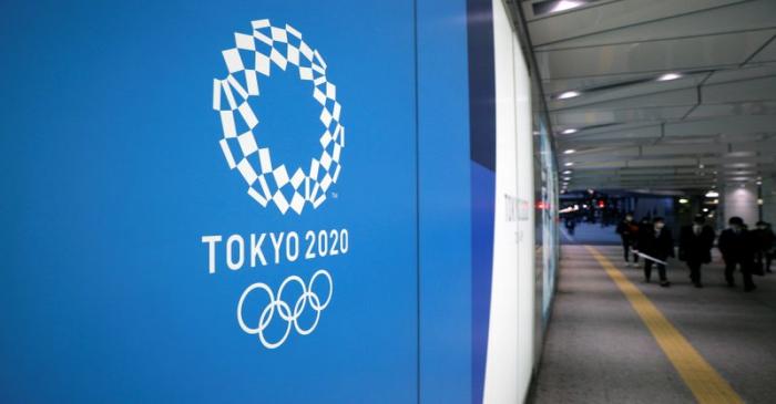 A man wearing a protective mask in front of an advertising billboard of Tokyo Olympics 2020,