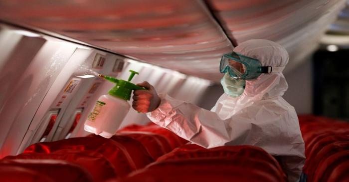A cleaning worker sprays disinfectant inside the cabin of a Lion Air's Boeing 737-800 at
