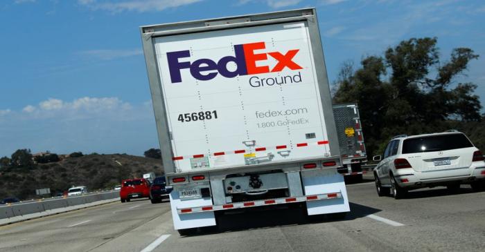 A Federal Express Ground truck travels down a highway through Carlsbad, California