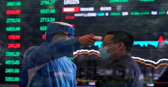 FILE PHOTO: A worker wearing a protective suit takes body temperature measurement of a man