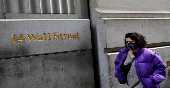 FILE PHOTO: A person wearing a face mask walks along Wall Street after further cases of