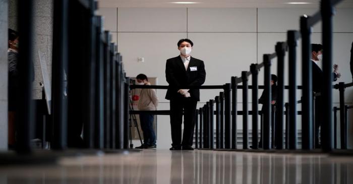 An employee wearing a mask to prevent contracting the coronavirus waits for a shareholder of