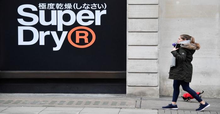 A woman walks past a window display at a Superdry store in London