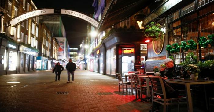 A man sits alone outside a pub on Carnaby Street, as the number of coronavirus (COVID-19) cases