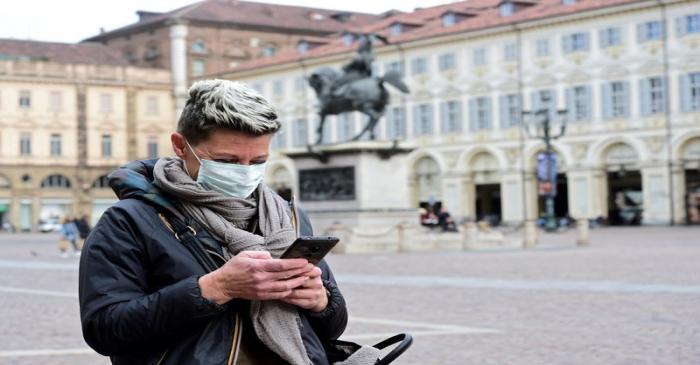 FILE PHOTO: Woman wearing a protective mask uses her mobile phone, as a coronavirus outbreak
