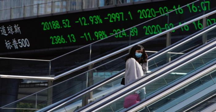 Pedestrian wearing a face mask rides an escalator near an overpass with an electronic board