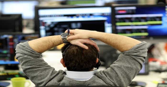 A broker looks at financial information on computer screens on the IG Index trading floor