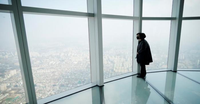 A woman wearing a mask to prevent contracting the coronavirus looks at a view of central Seoul