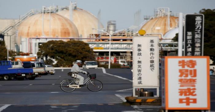 FILE PHOTO: A worker riding a bicycle passes the Fuji Oil Co.'s Sodegaura Refinery in Sodegaura