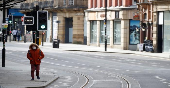 A man wears a mask as he walks along a deserted street amid the coronavirus outbreak in