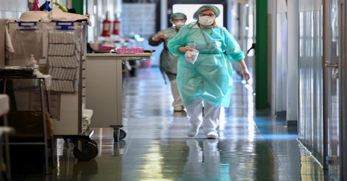 Medical workers wearing protective masks and suits walk in an intensive care unit at the Oglio