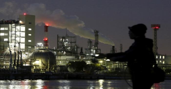 FILE PHOTO: Smoke is emitted from a chimney as a man fishes at the Keihin industrial zone in