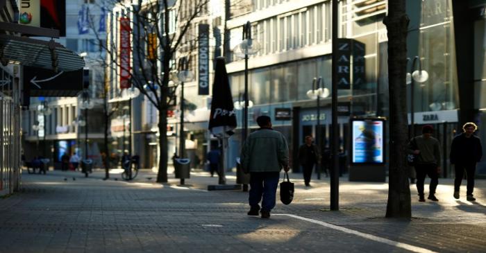 People walk in the main shopping street as shops are closed during the spread of the