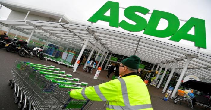 FILE PHOTO: A worker pushes shopping trolleys at an Asda store in west London, Britain