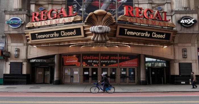 FILE PHOTO: A man cycles past a shuttered movie theater in Manhattan's Times Square following