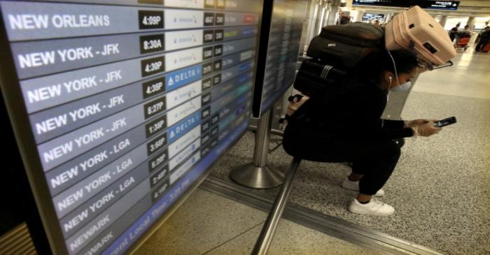 A passenger wearing a mask sits at Miami International Airport