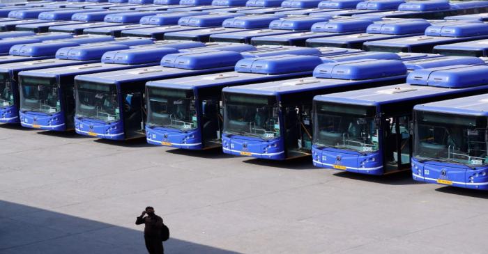 A man stands as buses are seen parked at a depot during lockdown by the authorities to limit
