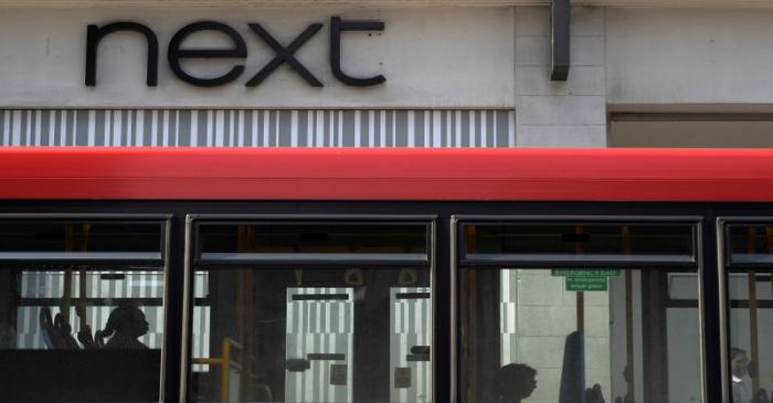 FILE PHOTO: A bus passes a branch of Next retail in London, Britain