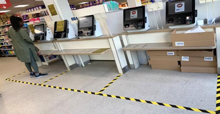 A customer stands in a taped off check-out area designed to separate shoppers in a supermarket,