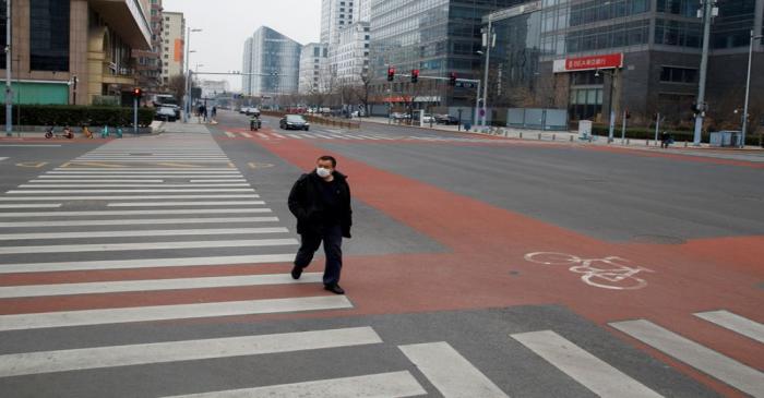 FILE PHOTO: A man wears a face mask as he crosses a street in the Central Business District in
