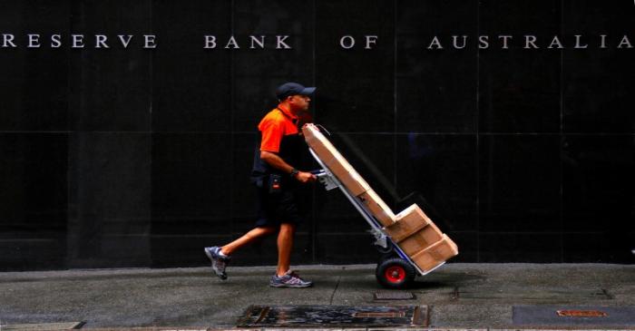 A worker delivering parcels pushes a trolley past the Reserve Bank of Australia building in