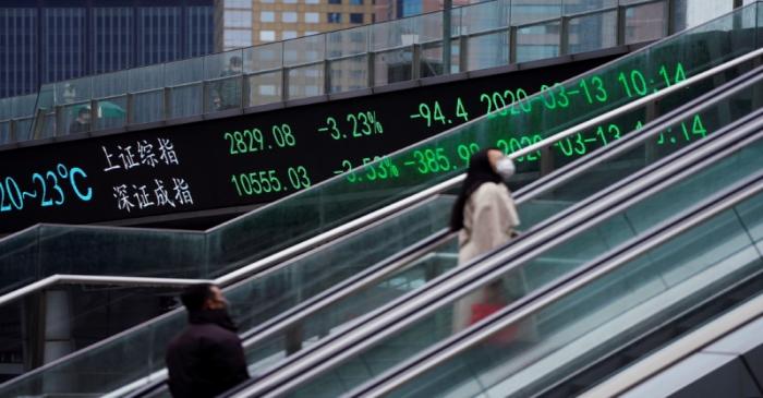 FILE PHOTO: Pedestrians wearing face masks ride an escalator near an overpass with an