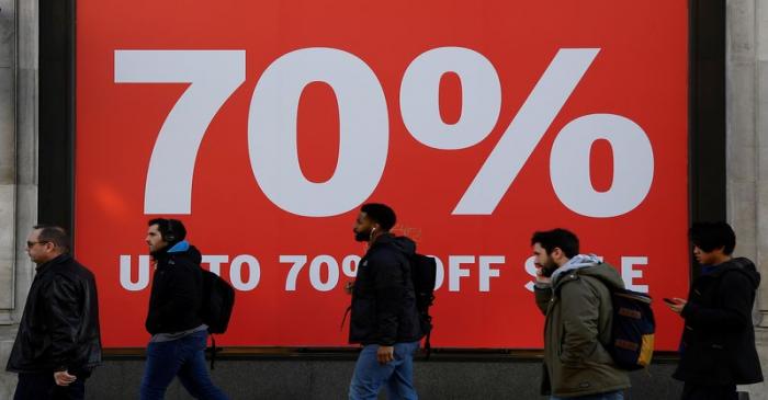 FILE PHOTO: Pedestrians pass a sale sign on a retail shop on Oxford Street in London