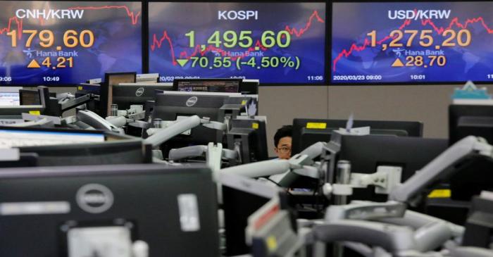 A currency dealer works in front of electronic boards showing the Korea Composite Stock Price