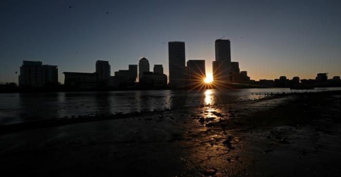 The sun rises behind the Canary Wharf financial district in London