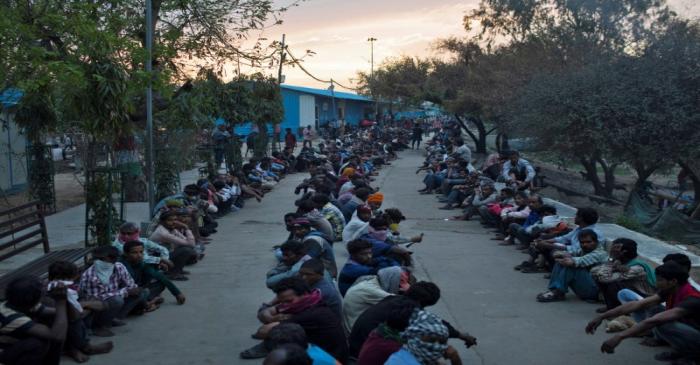 Daily wage workers and homeless people wait for food outside a government-run night shelter