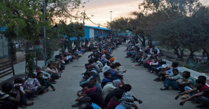 Daily wage workers and homeless people wait for food outside a government-run night shelter