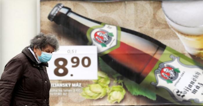 A woman walks past a beer advertisement billboard in Prague