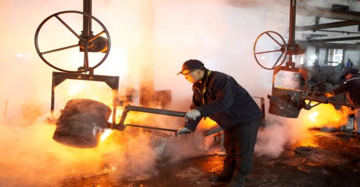FILE PHOTO: Worker pours molten iron into a mould at a mill manufacturing marine engine