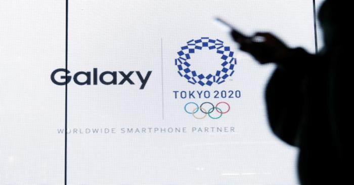 A woman uses her smartphone as an electric screen displaying logos of Tokyo 2020 Olympic Games