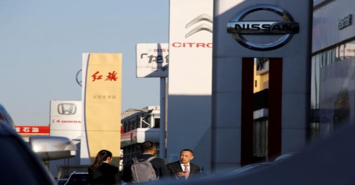 FILE PHOTO: People walk near the showrooms of Chinese and foreign car dealerships in Beijing