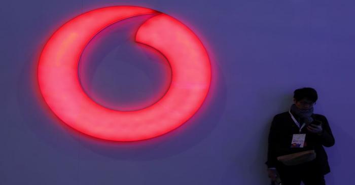 FILE PHOTO:  A man checks his mobile phone next to a Vodafone logo at the Mobile World Congress