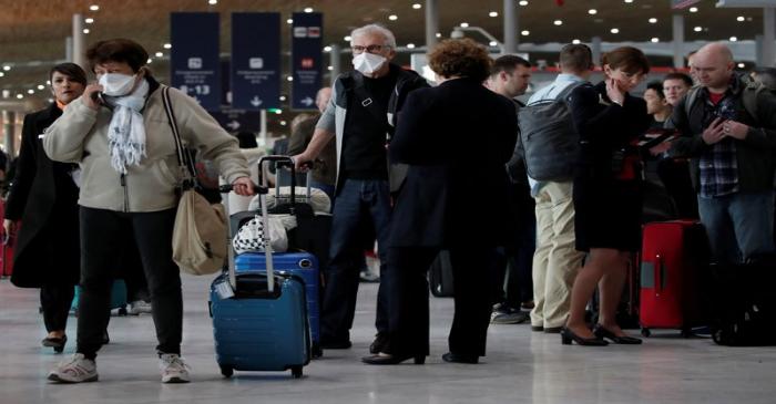 Travellers wearing protective face masks ask for information inside Terminal 2E at Paris