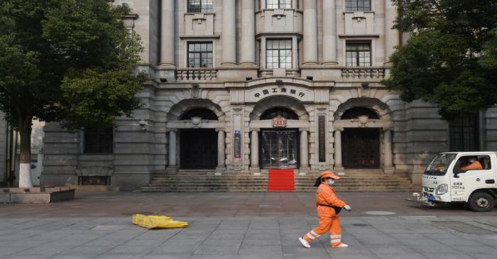 FILE PHOTO: Sanitation worker wearing a face mask walks past a branch of ICBC in Wuhan