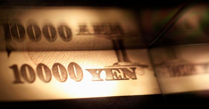 Light is cast on a Japanese 10,000 yen note as it's reflected in a plastic board in Tokyo, in