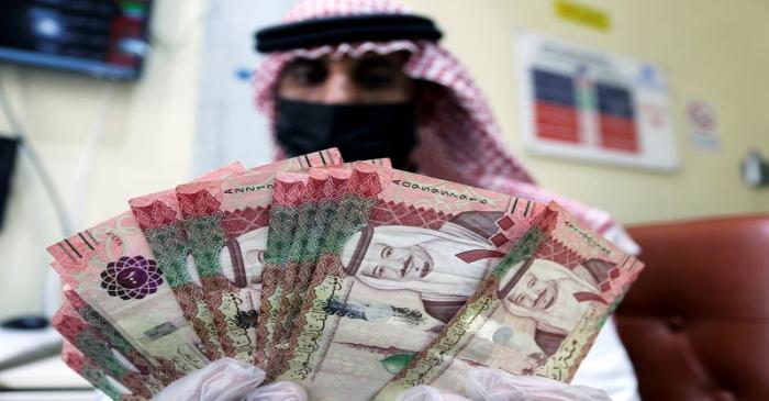 FILE PHOTO: A Saudi money exchanger wears a protective face mask and gloves, as he counts Saudi