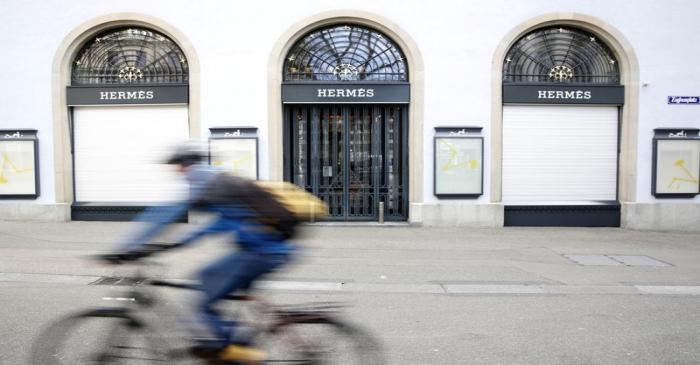 Man cycles past a closed shop of French luxury fashion brand Hermes in Zurich