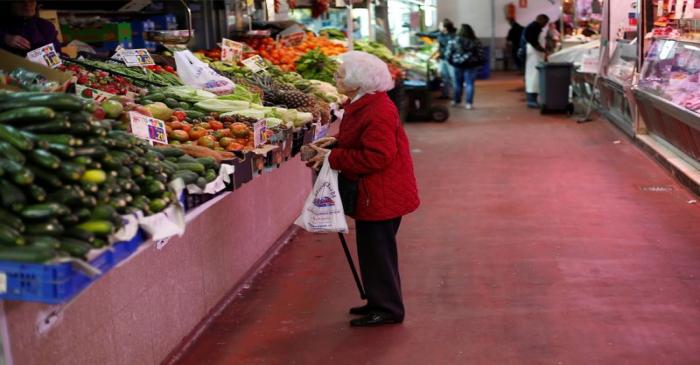 A woman looks at fruits and vegetables at a market stall in Madrid