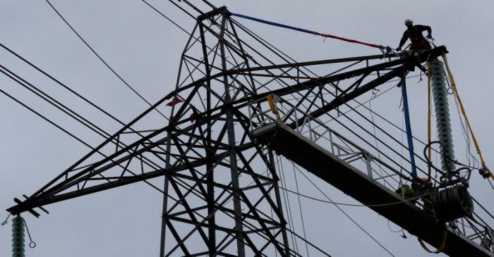 An engineer stands on top of an electricity pylon as he carries out maintenance work near