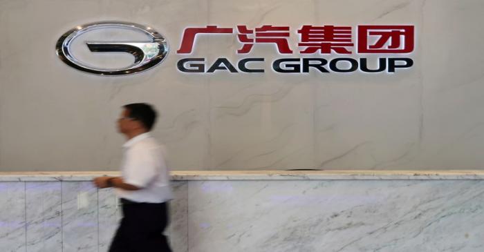 FILE PHOTO: Man walks past the logo of Chinese automobile maker GAC Group at the company